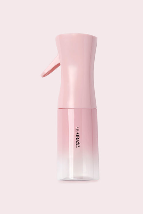 Pink spray bottle with gradient design on a light pink background