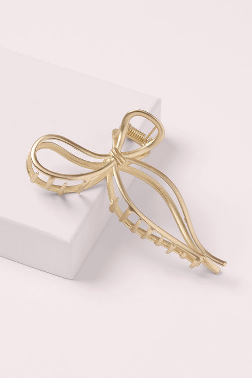 The Hair Edit Gold Gilded Bow Claw Clip on a pink box
