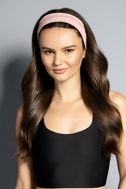 Woman wearing a pink headband against a gray background