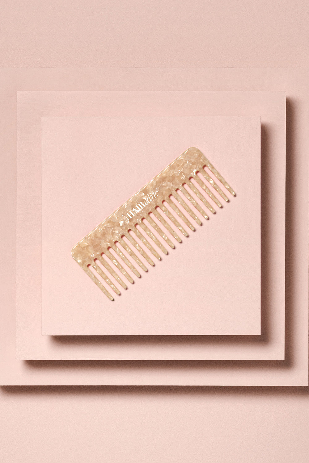the hair edit untangle and glide beige comb on stacked boxes