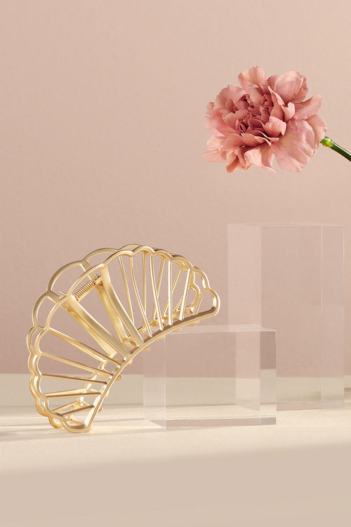 The Hair Edit Large Gold Gilded Mermaid Shell Claw Clip in a lifestyle setting with flowers