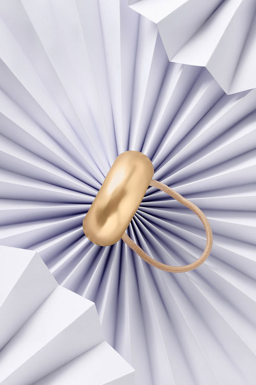 The Hair Edit Brilliant Cuff Arched Gold Metal Hair Tie on blue paper