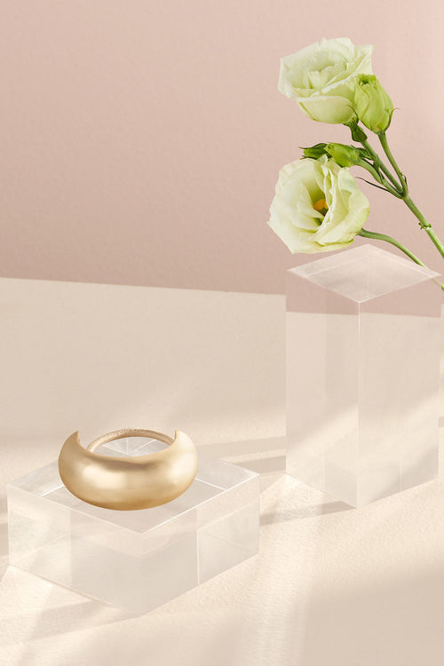 The Hair Edit Brilliant Cuff Arched Gold Metal Hair Tie in a lifestyle setting with flowers