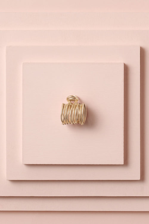 Camellia Gilded Wrap Cuff Claw Clip on a stack of pink boxes