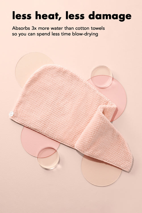 Pink towel with text about water absorption and heat damage reduction on a beige background