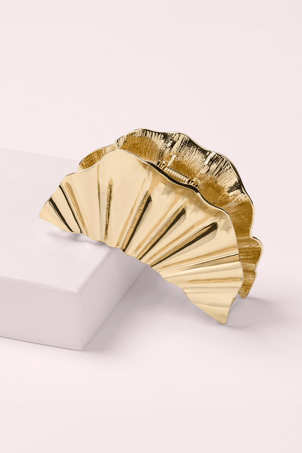 Gold decorative claw clip with a fan-like design on a pink background1