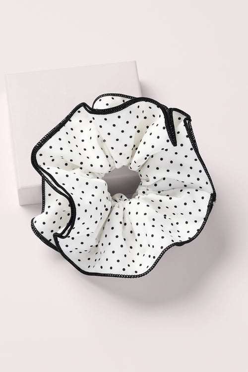 White and black polka dot oversized scrunchie on a pink background