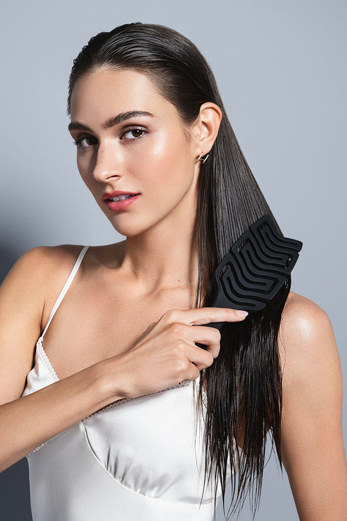 model with wet hair brushing her hair