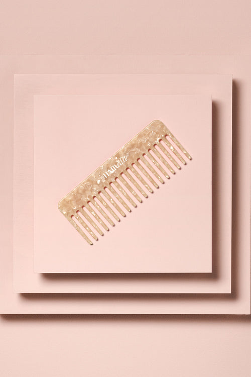 the hair edit untangle and glide beige comb on stacked boxes