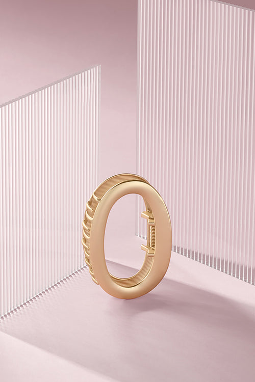 The Hair Edit Gilded Contour Claw Clip against a pink background 