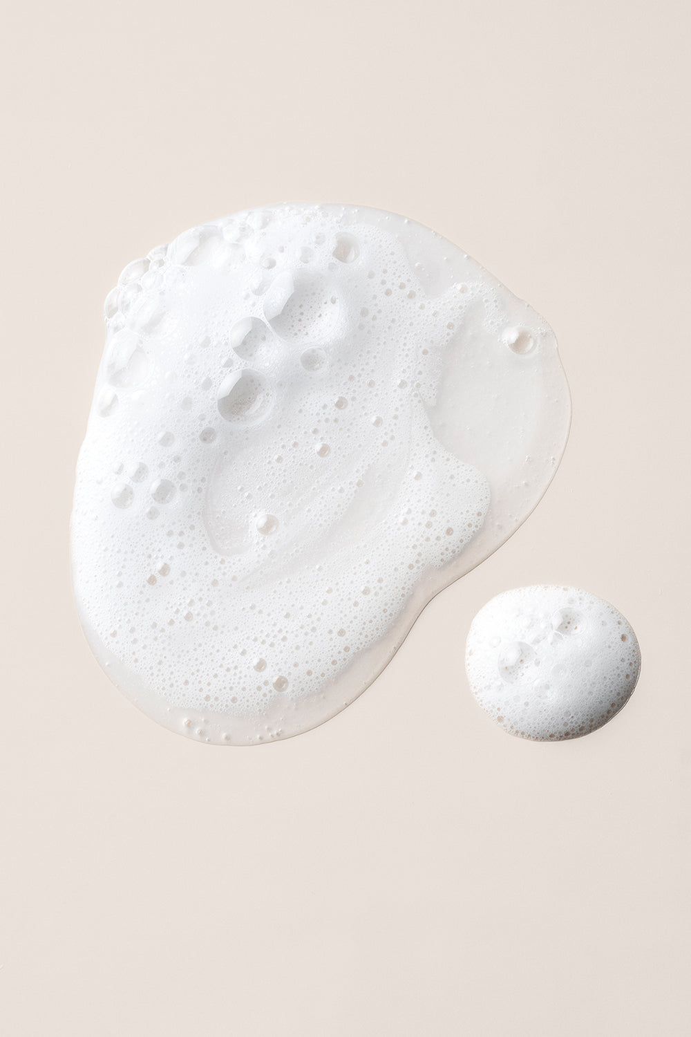 Close up of The Hair Edit Shampoo Concentrate foam texture on a beige background9