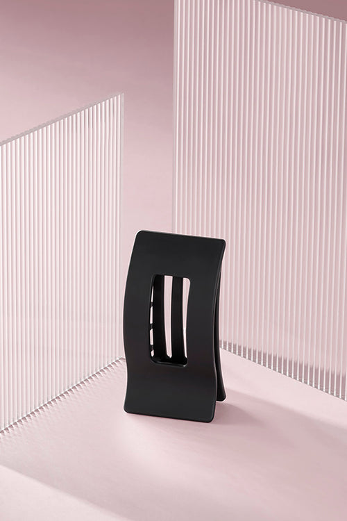 A black rectangle flat lay claw clip on a pink background