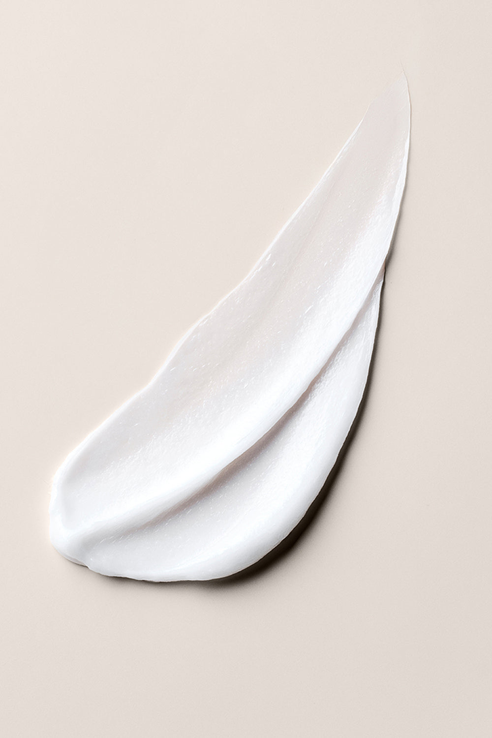 Close up of The Hair Edit Hair Mask Concentrate creamy texture on a beige background8