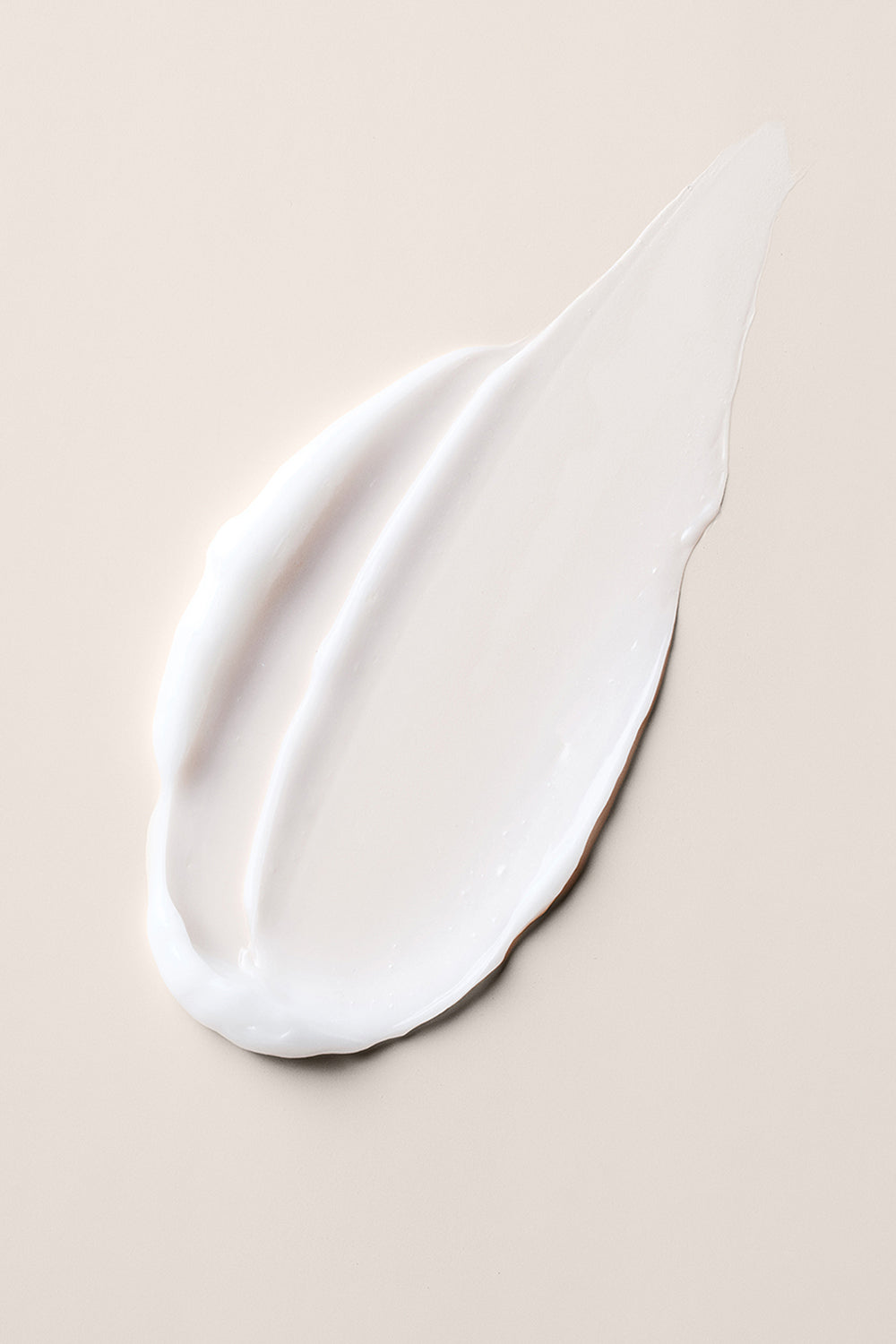 Close up of The Hair Edit Multi Benefit Leave-In Conditioner creamy texture on a beige background7