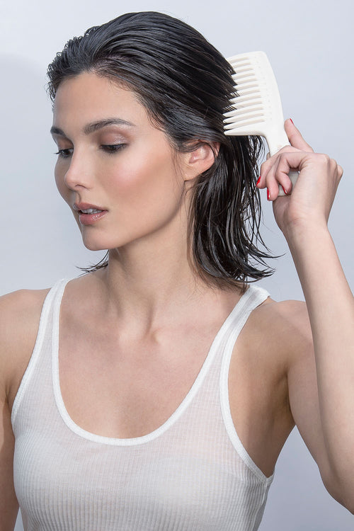 model with short wet hair combing her hair with the hair edit tame and condition comb