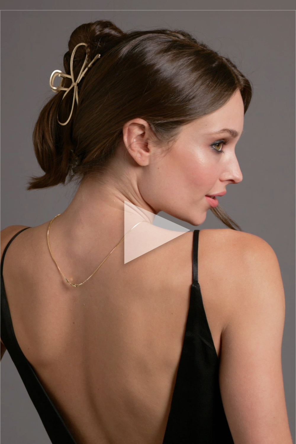 A brunette model wearing The Hair Edit Gilded Festive Claw Clip in her hair as a French twist2